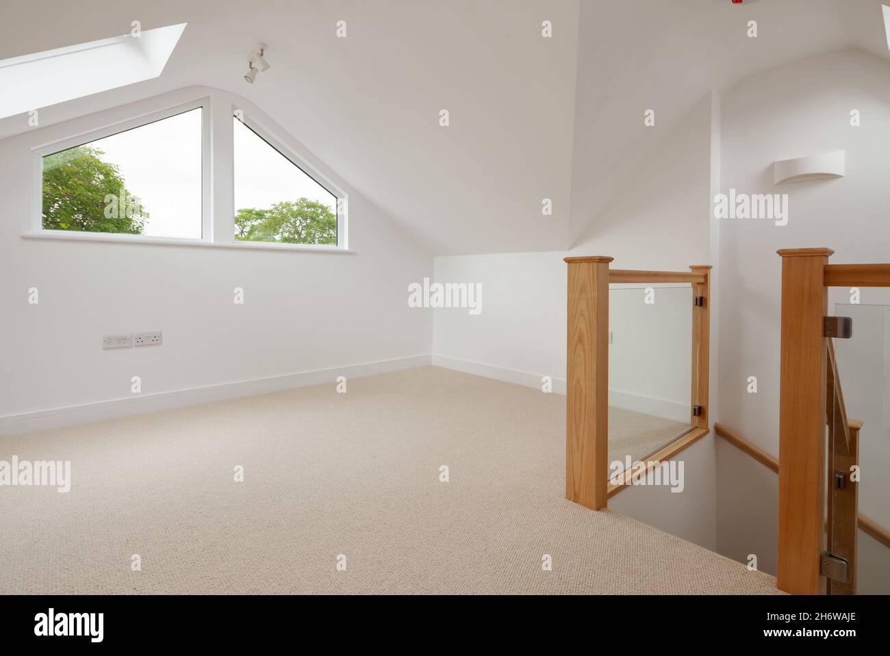Cambridge, England - Juli 31 2019: Leeres Dachgeschoss-Loft-Zimmer im renovierten Haus mit natürlicher Holztreppe Stockfoto