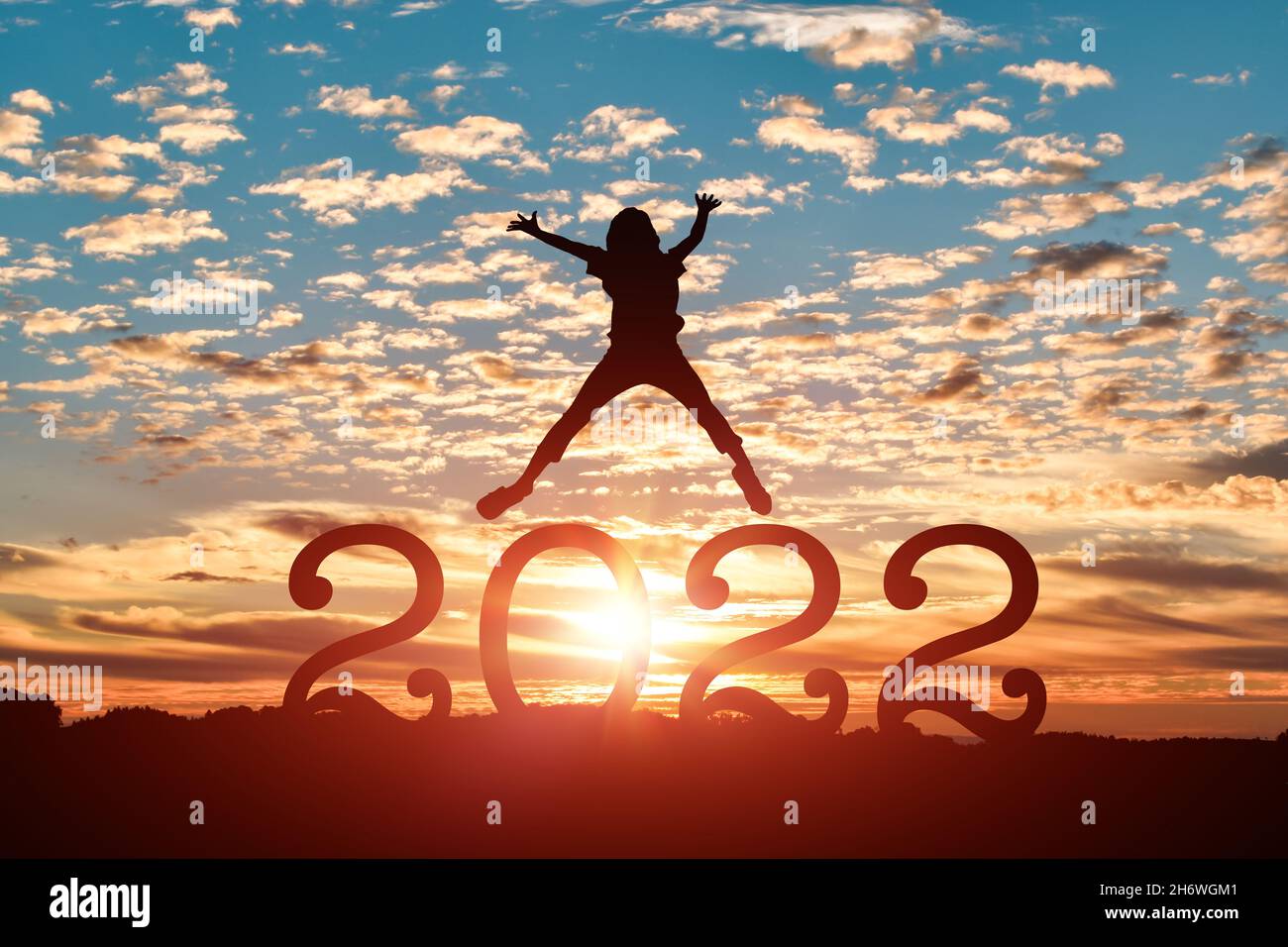 Silhouette einer jungen Frau, die im Hintergrund bei Sonnenuntergang oder Sonnenaufgang zum glücklichen neuen Jahr 2022 springt. Stockfoto