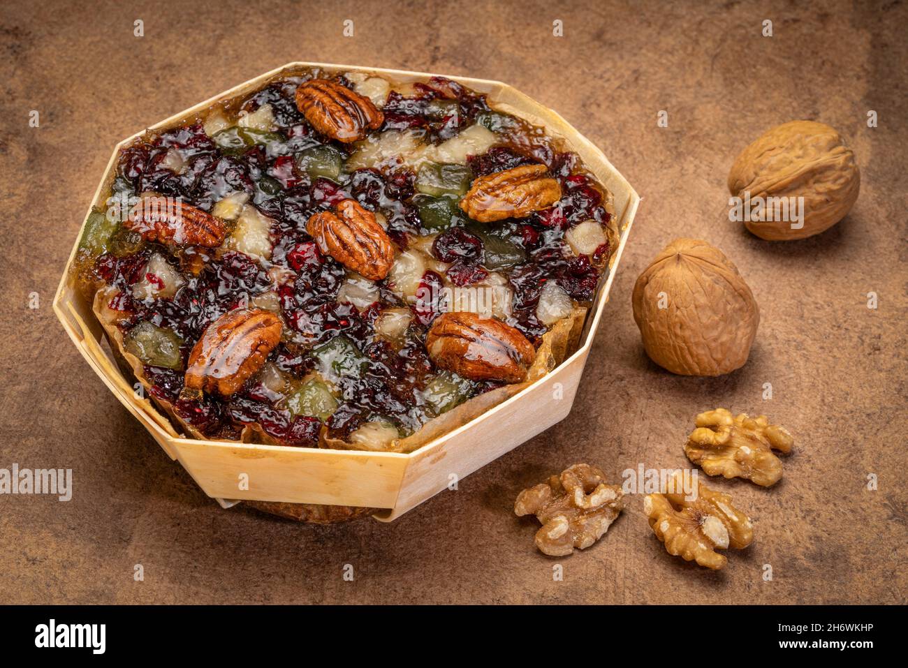 Urlaub Rum Kuchen mit Pekannüssen, Kirschen und Walnüssen auf einem grunge Rindenpapier Stockfoto