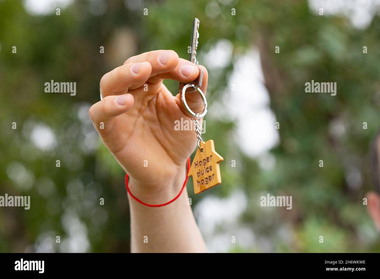 Hand zeigt Schlüssel mit Schlüsselanhänger eines Mini House.New Home Konzept. Stockfoto