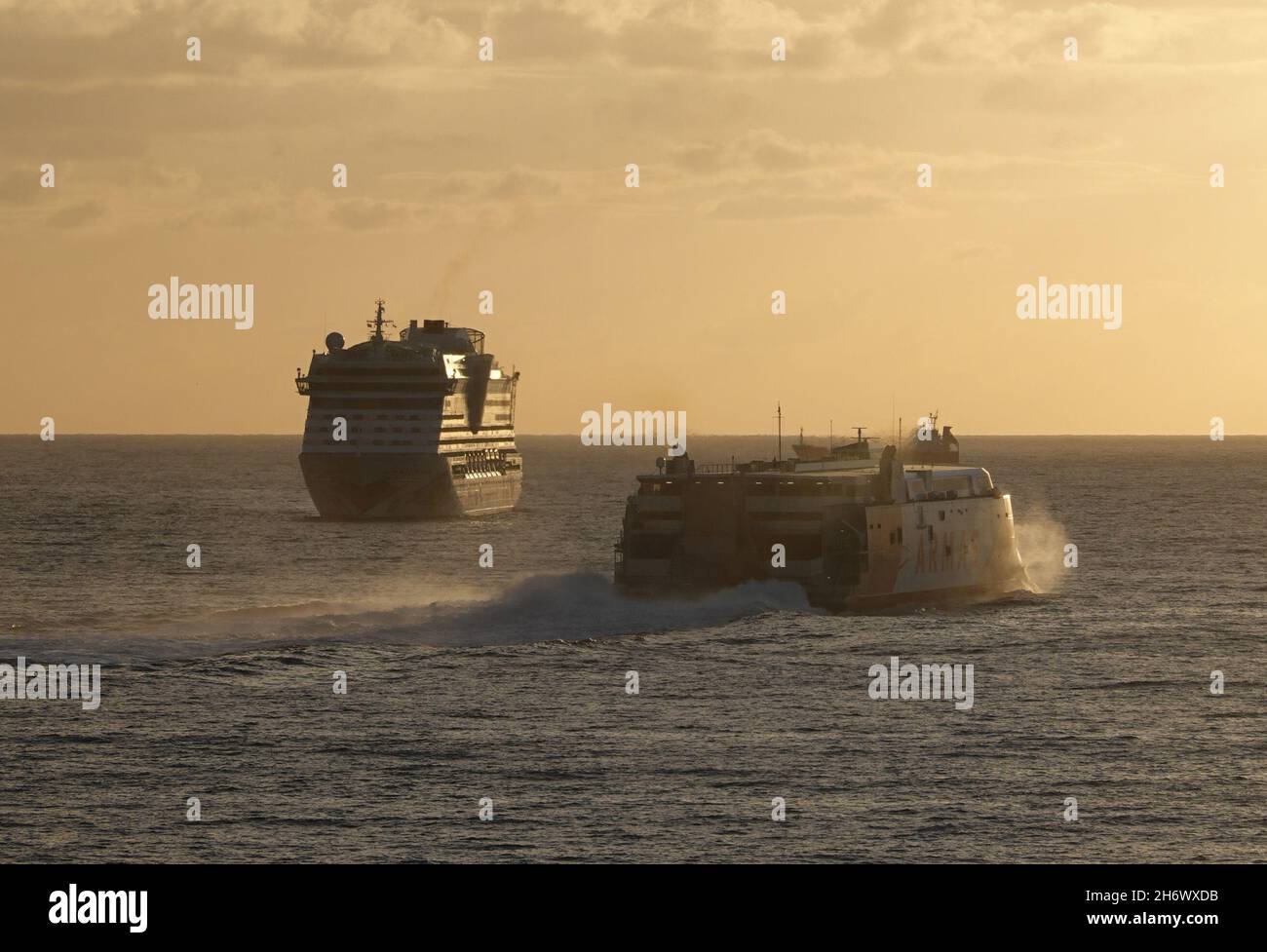 26. Oktober 2021, Spanien, Teneriffa: Das Kreuzschiff Aida bella (l) wartet am Morgen, bevor es die Liegeposition im Hafen von Santa Cruz de Tenerifa erreicht. Die Fähre Armas fährt auf der rechten Seite vorbei. Die AIDAbella, die unter Aida Cruises segelt, gehört der Carnival Corporation & plc. Das Vereinsschiff der Kreuzfahrtflotte wurde auf der Meyer-Werft in Papenburg gebaut, die Kielverlegung erfolgte 2007. Foto: Soeren Sache/dpa-Zentralbild/ZB Stockfoto