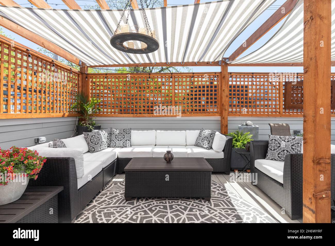 Eine gemütliche Dachterrasse mit überdachten Pergolen über der Oberseite, Gartenmöbel, und die Sonne, die durch. Stockfoto