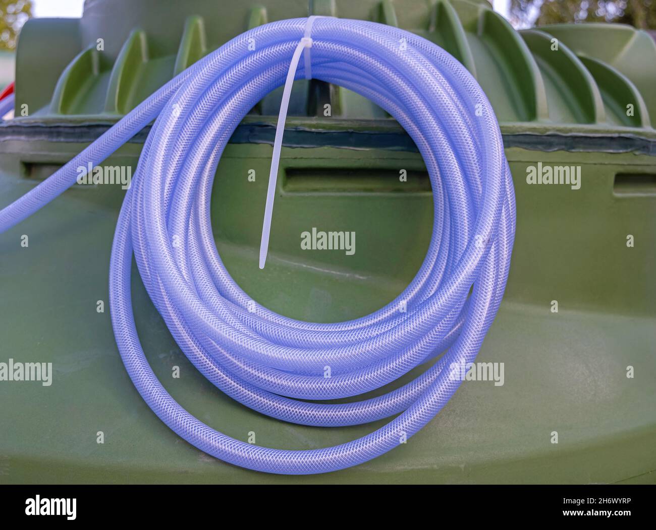 Gummischlauchspule am großen Kunststoffwassertank Stockfoto