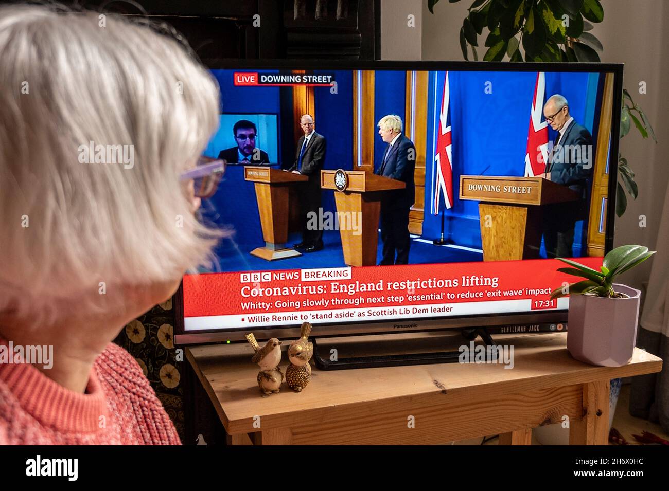Boris Johnson kündigt im BBC TV an, dass die Beschränkungen von Covid aufgehoben werden sollen; dies wird von einer älteren Frau beobachtet. 12/07/2021. Stockfoto