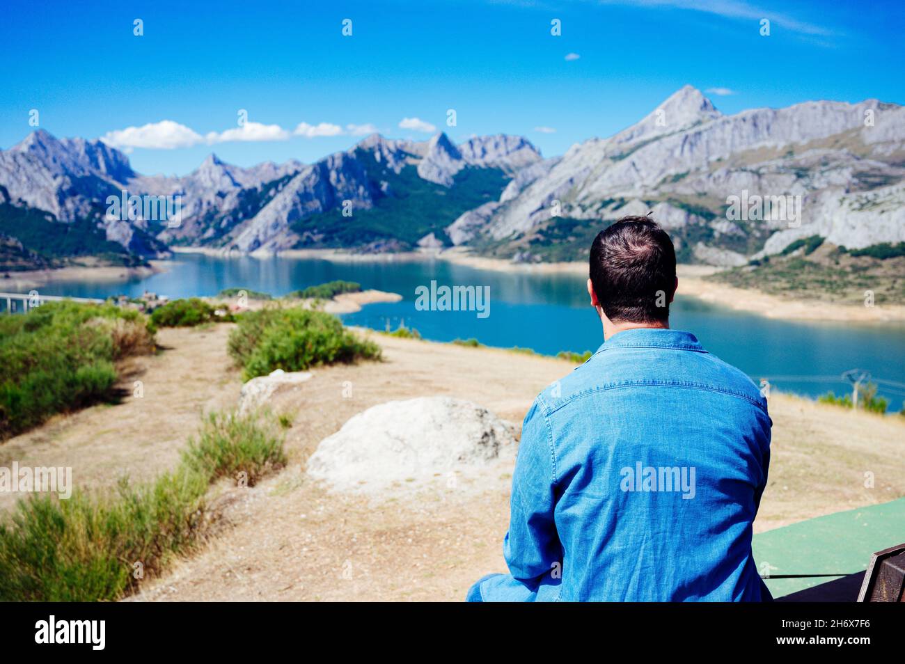 Junger Mann sitzt mit dem Rücken in den Bergen von Riano auf den Picos de Europa Stockfoto