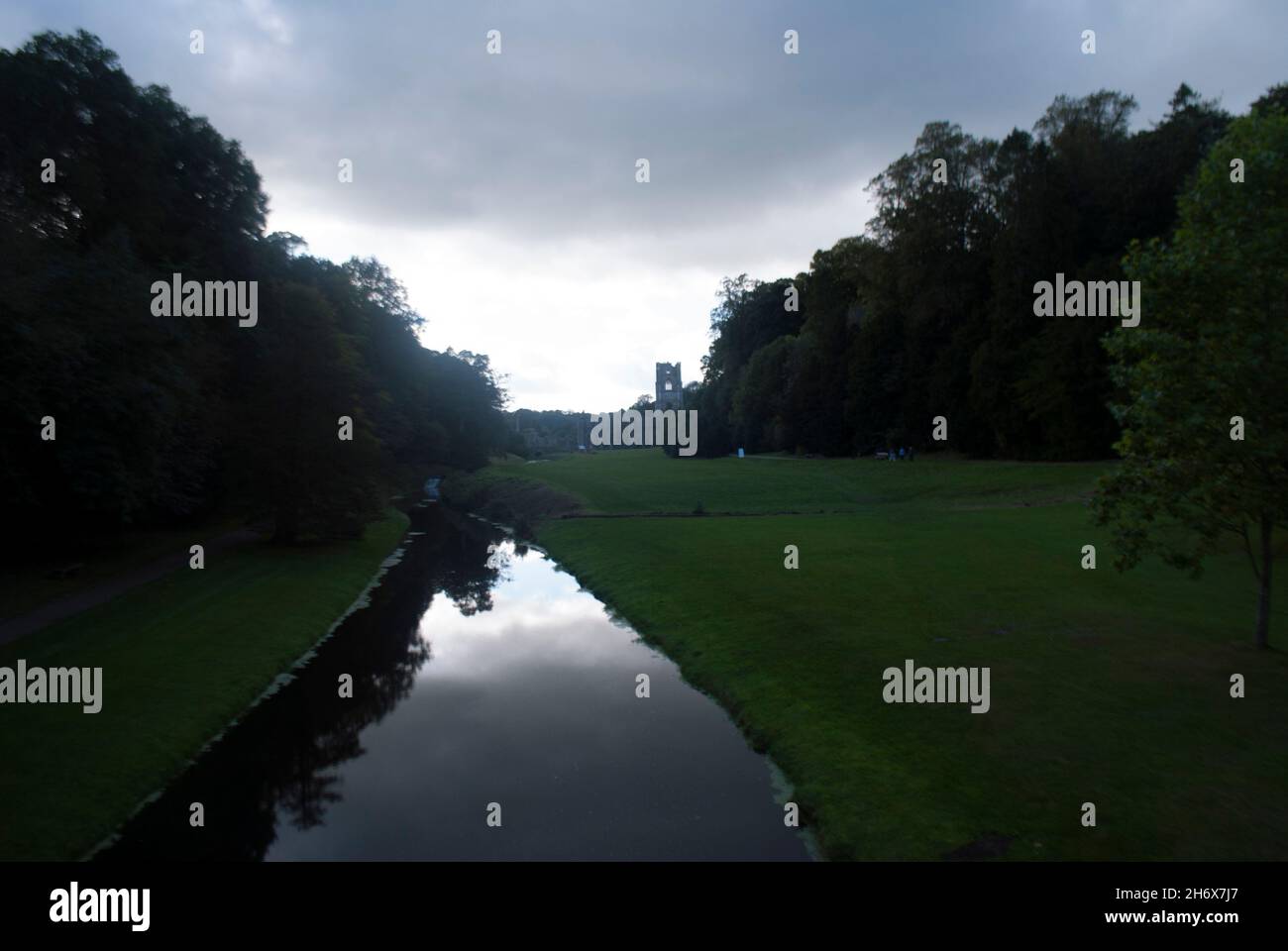 River Skell und Silhouetted Tower of Fountains Abby bei Sonnenuntergang, Studley Royal Park, Fountains Abbey, Aldfield, in der Nähe von Ripon, North Yorkshire, England Stockfoto