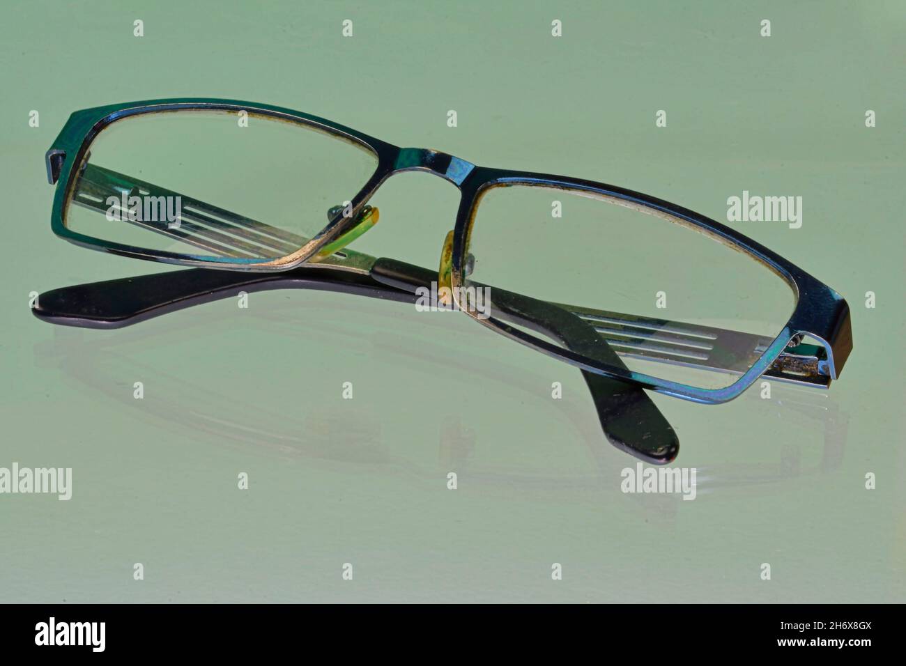 Spiegelung der Brille. Blaue Brillen, Nahaufnahme. Brillen. Brillen im alten Stil. Brille mit transparenten Gläsern. Vintage Gläser auf reflektierten Stockfoto