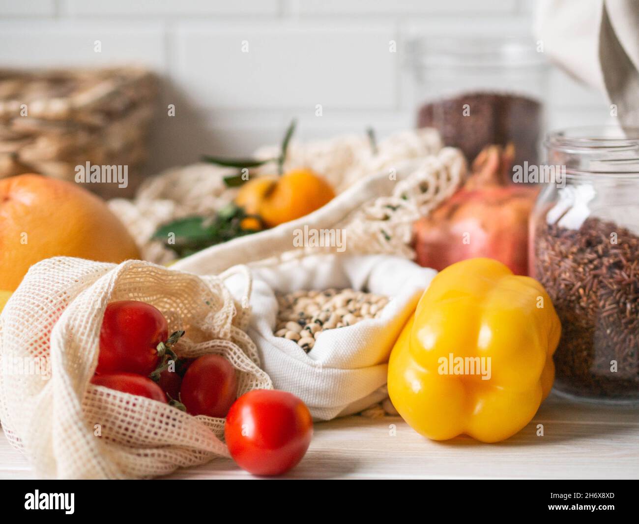 Frisches Gemüse und Obst in Öko-Baumwollbeuteln auf dem Tisch in der Küche. Zero Waste Shopping-Konzept. Vorderansicht. Speicherplatz kopieren. Stockfoto