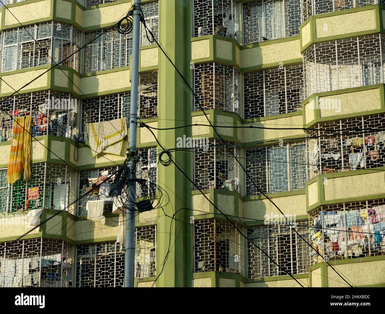 Enge Ernte eines Wohnblocks aus Wohnungen mit Waschanlagen, die von Balkonen hängen, Kalkutta, Indien Stockfoto