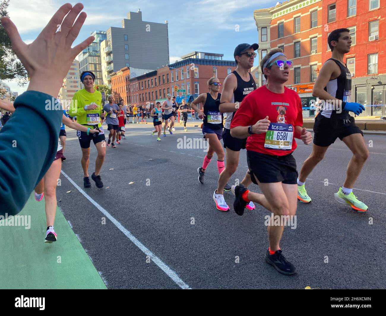 Die Zuschauer geben den Marathonläufern „High Fives“ als Ermutigung, wenn sie während des NYC-Marathons 2021 die 4th Avenue durch das Park Slope-Viertel von Brooklyn hochlaufen. Stockfoto
