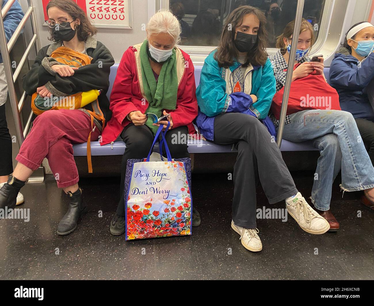 Obwohl die Menschen immer noch maskiert sind, während sie mit den U-Bahn-Zügen von New York City fahren, gibt es keinen Raum mehr für soziale Distanzierung. Stockfoto