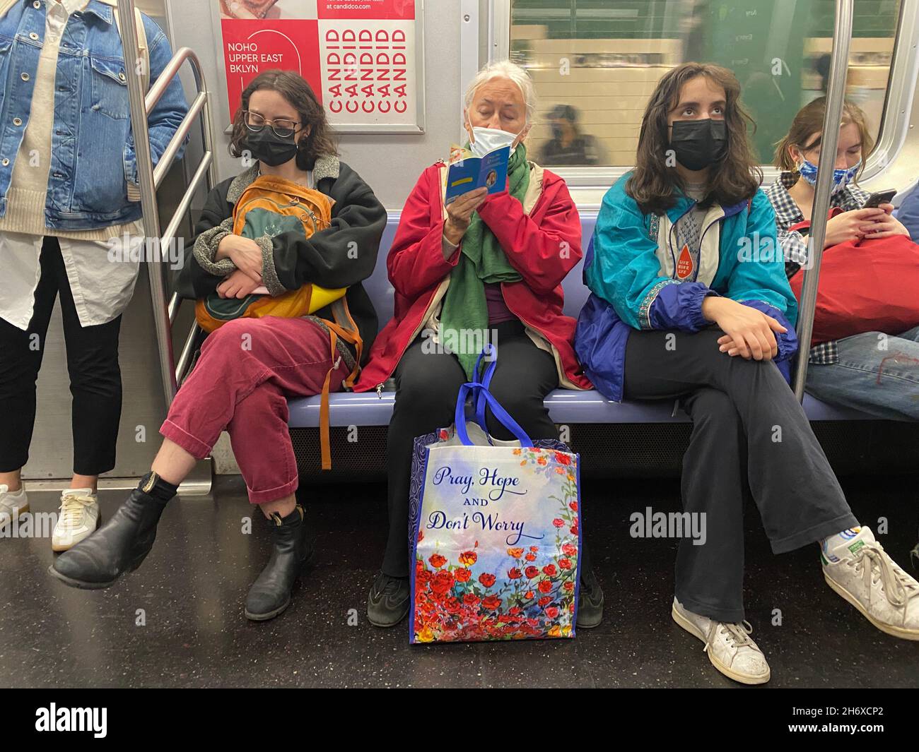 Obwohl die Menschen immer noch maskiert sind, während sie mit den U-Bahn-Zügen von New York City fahren, gibt es keinen Raum mehr für soziale Distanzierung. Stockfoto