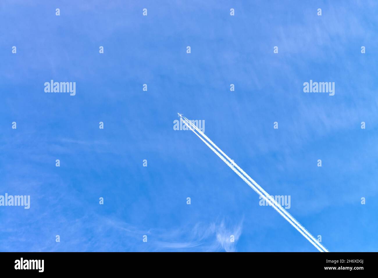 Hochfliegende Passagierflugzeuge, die einen weißen Kontrail gegen einen blauen Himmel verursachen Stockfoto