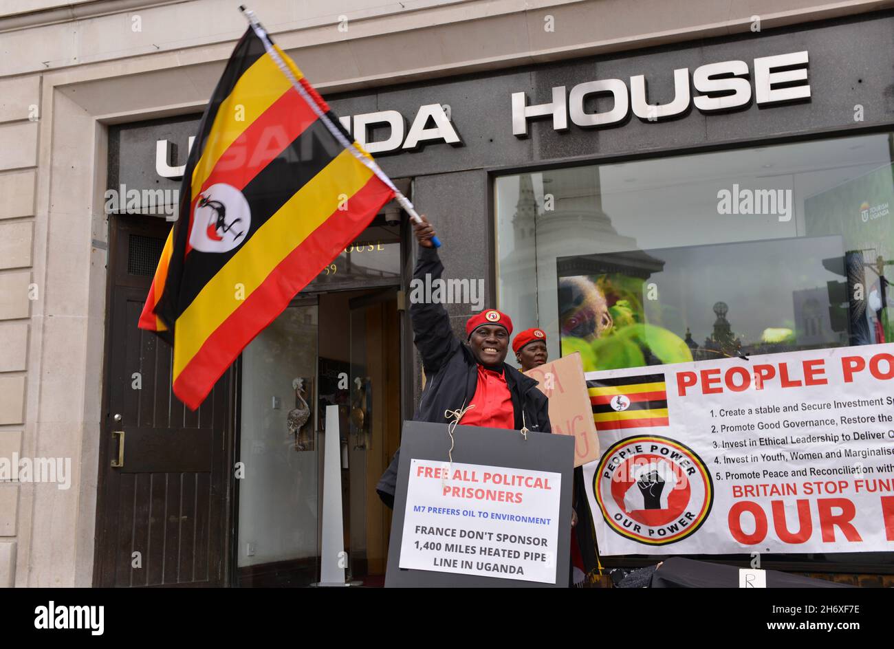 London, Großbritannien. November 2021. Während der Demonstration winkt ein Protestant auf dem Trafalgar Square eine ugandische Flagge gegenüber dem Uganda House.Ugander aus Großbritannien protestierten vor der Uganda High Commission in London und forderten die britische Regierung auf, sich gegen die Inhaftierung von politischen Aktivisten und Menschenrechtsverletzungen zu äußern. Kredit: SOPA Images Limited/Alamy Live Nachrichten Stockfoto