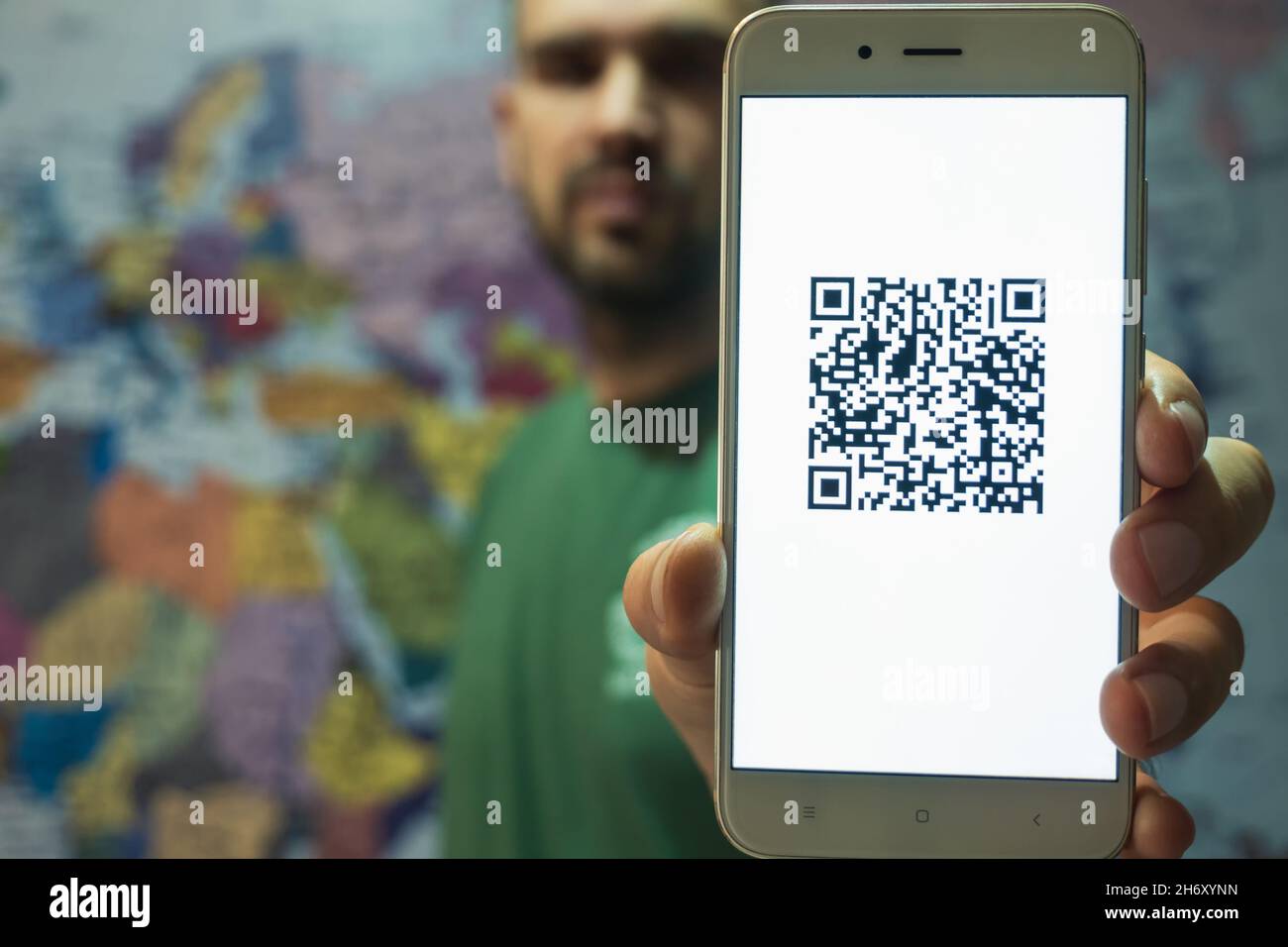 Ein Mann mit einem Smartphone auf dem Bildschirm QR-Code des Impfzertifikats Covid-19. Elektronischer Reise-Impfpass. Im Hintergrund ist ein Stockfoto