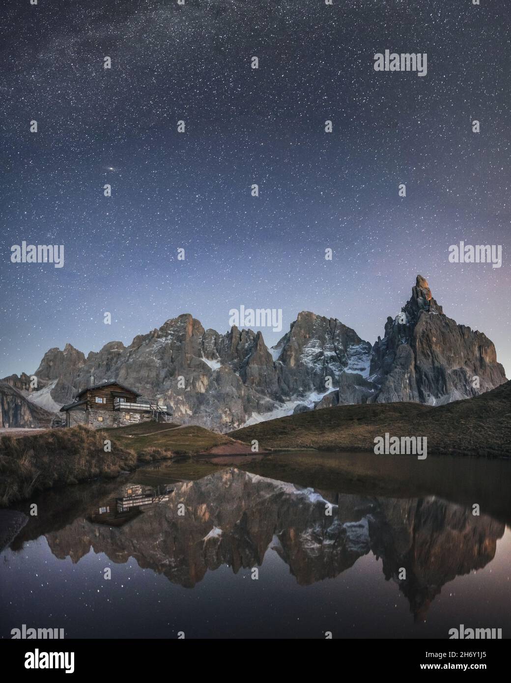 Unglaubliche Nachtlandschaft mit einer Reflexion des Sternenhimmels und der Berge in einem Wasser des kleinen Sees in einem beliebten Touristenziel - Baita Segantini Berghütte. Rollepass, Dolomiten Alpen, Italien Stockfoto