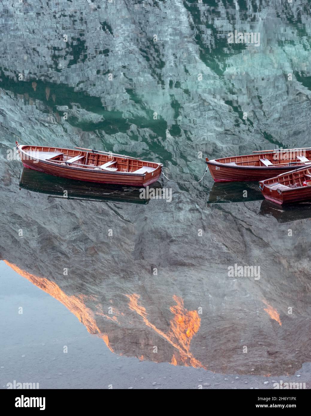 Malerische Landschaft mit dem berühmten Pragser See in den herbstlichen Dolomitenbergen. Holzboote im klaren Wasser des Pragser Sees, Dolomiten-Alpen, Italien. Glühender Seekofel Berggipfel in Wasserspiegelung Stockfoto