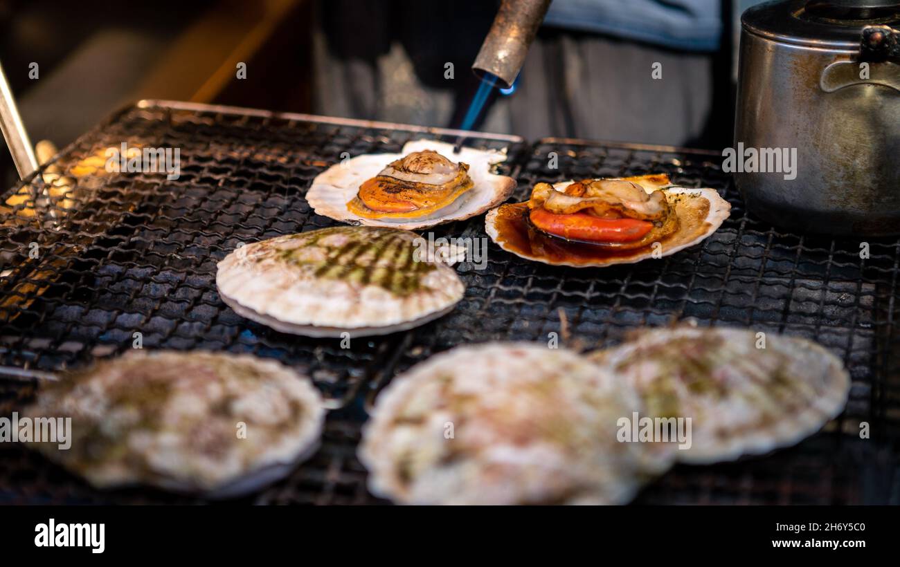 Händler verkaufen Jakobsmuscheln in Tsukiji Fischmarkt. Mann, der in Einzelhandelsgeschäften und Restaurants waren in Meeresfrüchten zubereitet, carter der Öffentlichkeit in Tokio. Berühmte m Stockfoto