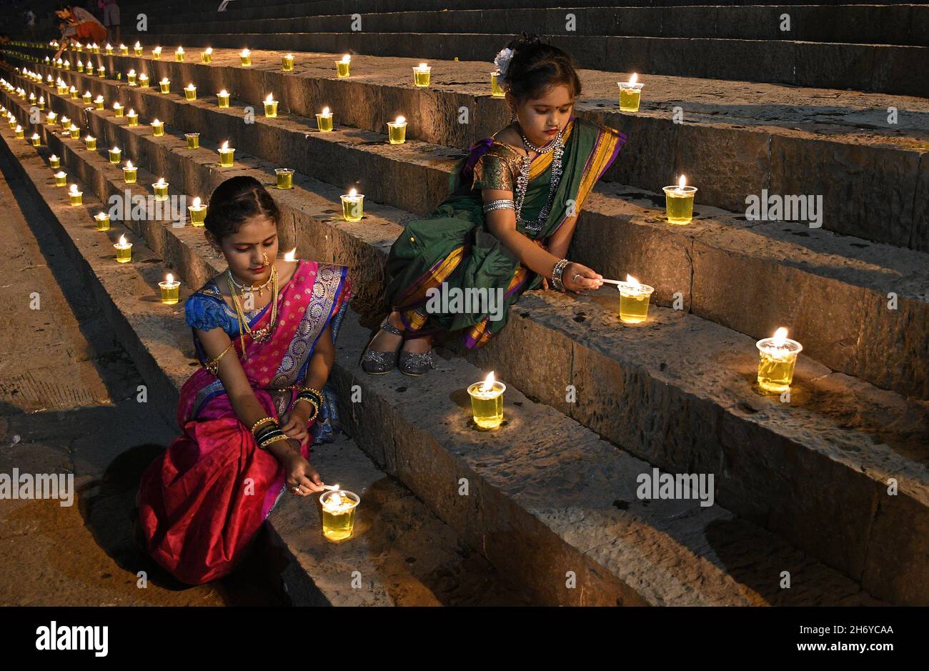 Mumbai, Indien. November 2021. Die Kinder, die in einem traditionellen Saree gekleidet waren, sahen während der Feier eine Diya (irdene Lampe) im Banganga-Wasserbehälter anzünden. Dev Diwali wird von Hindus durch das Anzünden von Diyas (irdenen Lampen) gefeiert. Es gedenkt auch Lord Shivas Sieg über die Asuras (Dämonen). Kredit: SOPA Images Limited/Alamy Live Nachrichten Stockfoto