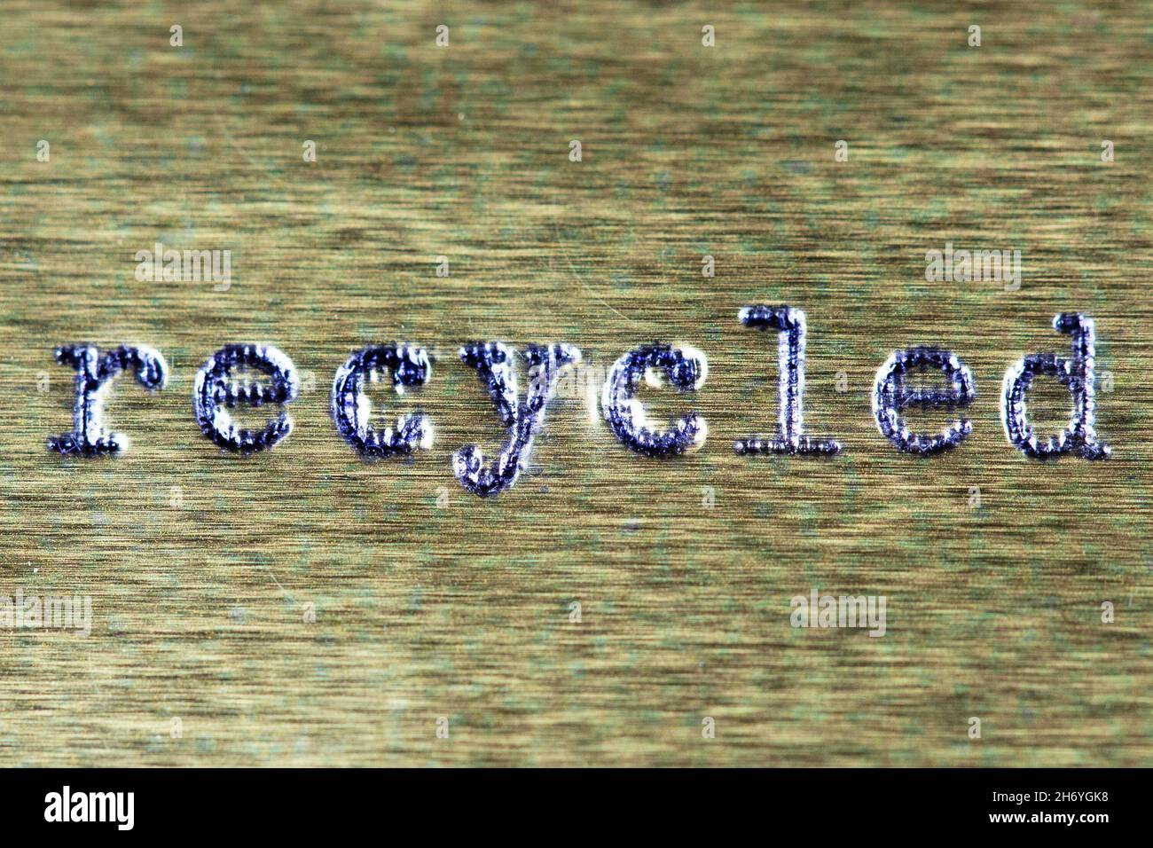Das Wort 'rezykliert' in der alten Schreibmaschinenschrift auf metallischer Oberfläche. Stockfoto