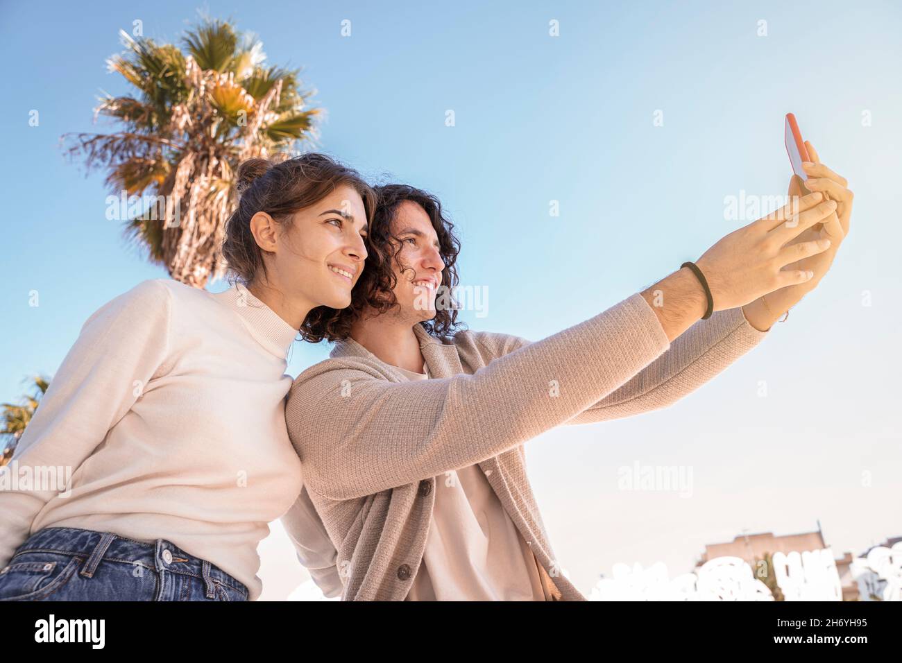 Paar unter blauem Himmel machen Selfie mit Handy Stockfoto