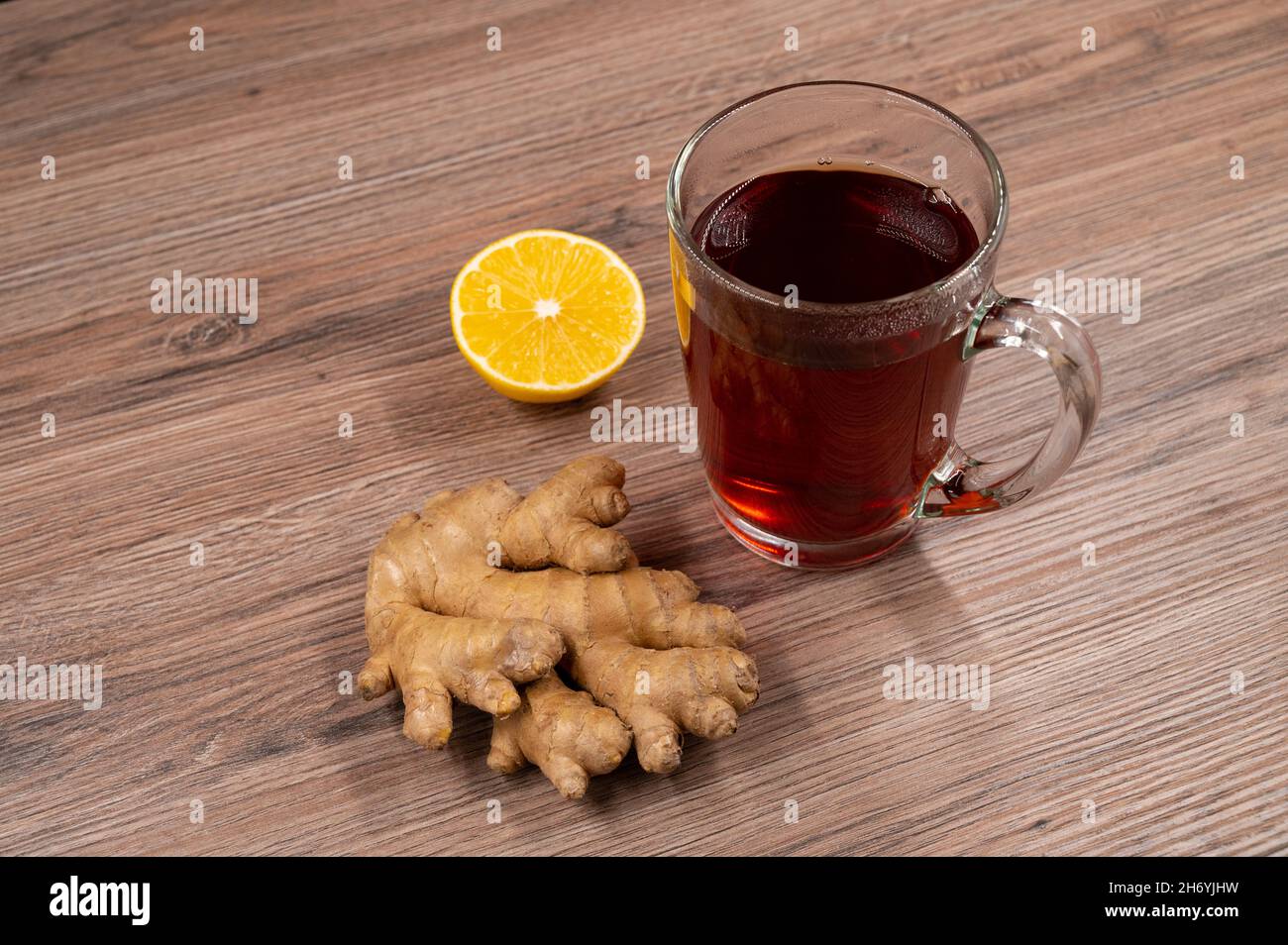 Heißer Tee mit einer Hälfte Zitronen- und Ingwerwurzel auf einem Holztisch. Draufsicht. Stockfoto