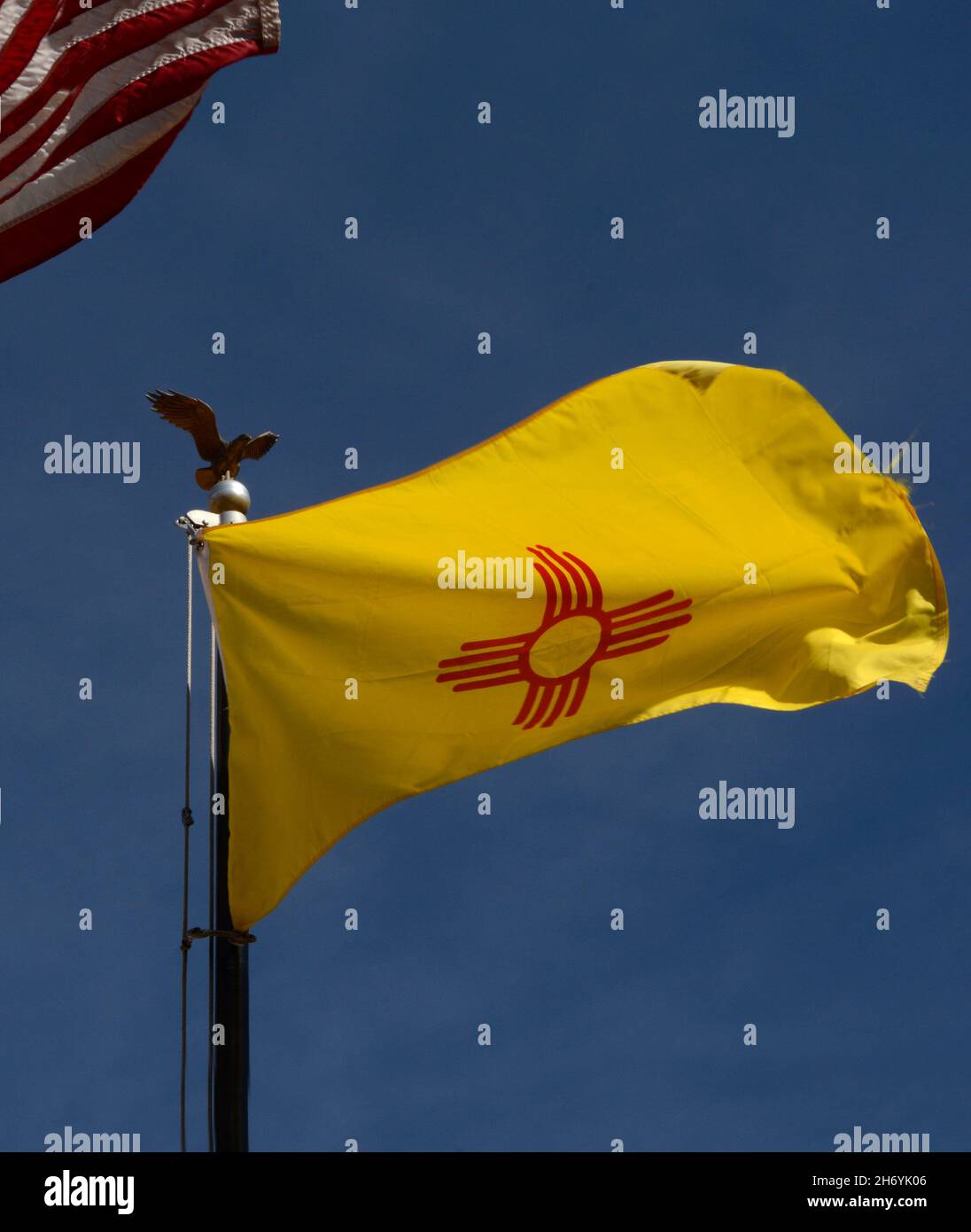 Die Staatsflagge von New Mexico mit ihrem indianischen Sonnensymbol fliegt neben einer Flagge der Vereinigten Staaten in Santa Fe, New Mexico. Stockfoto