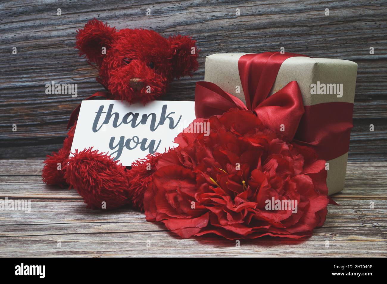 Dankeskarte mit Geschenkbox Geschenk und Blumendekoration auf Holzhintergrund Stockfoto