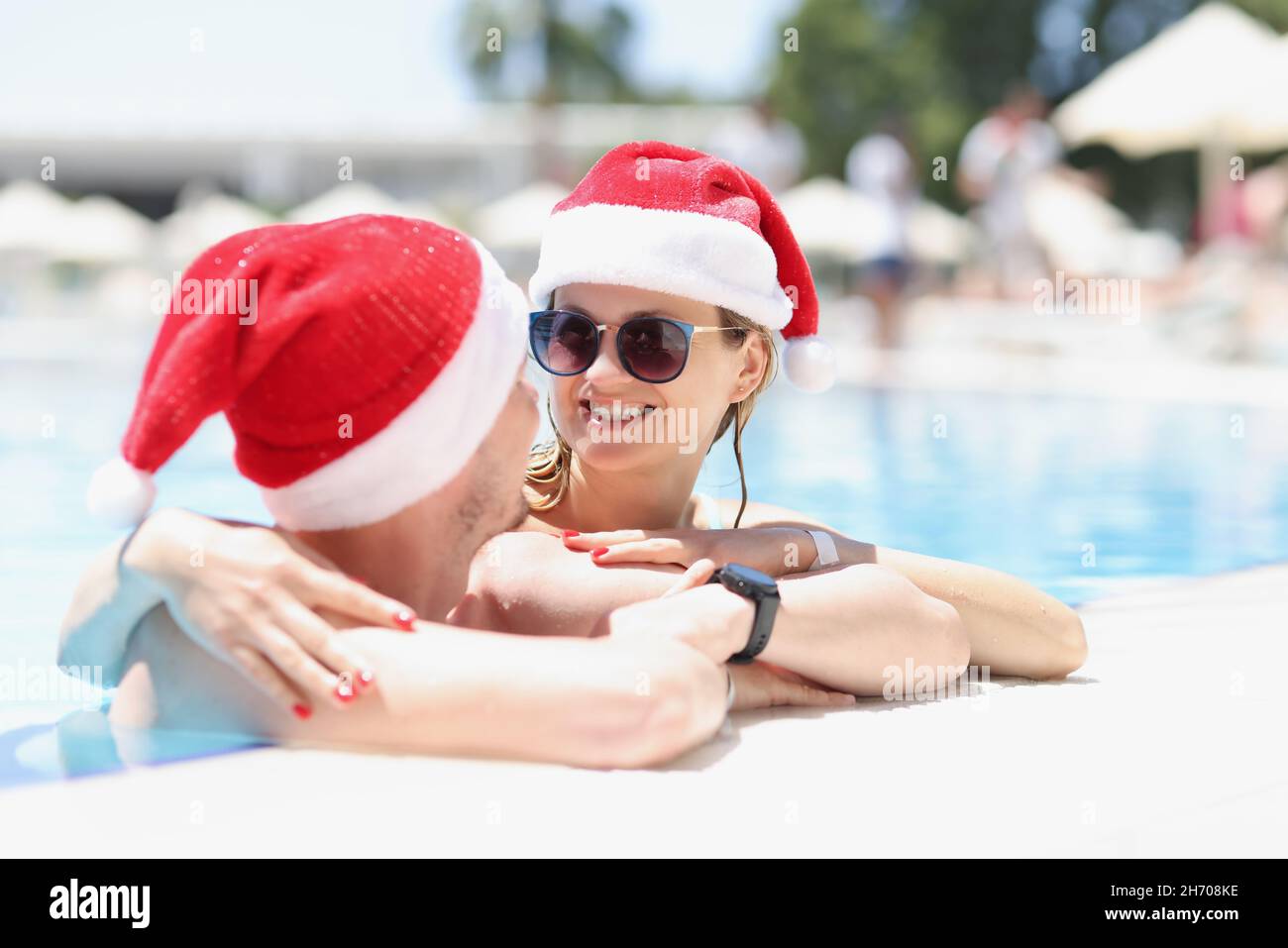 Frau umarmt Mann und lächeln zu ihm tragen weihnachtsmann Hut Stockfoto