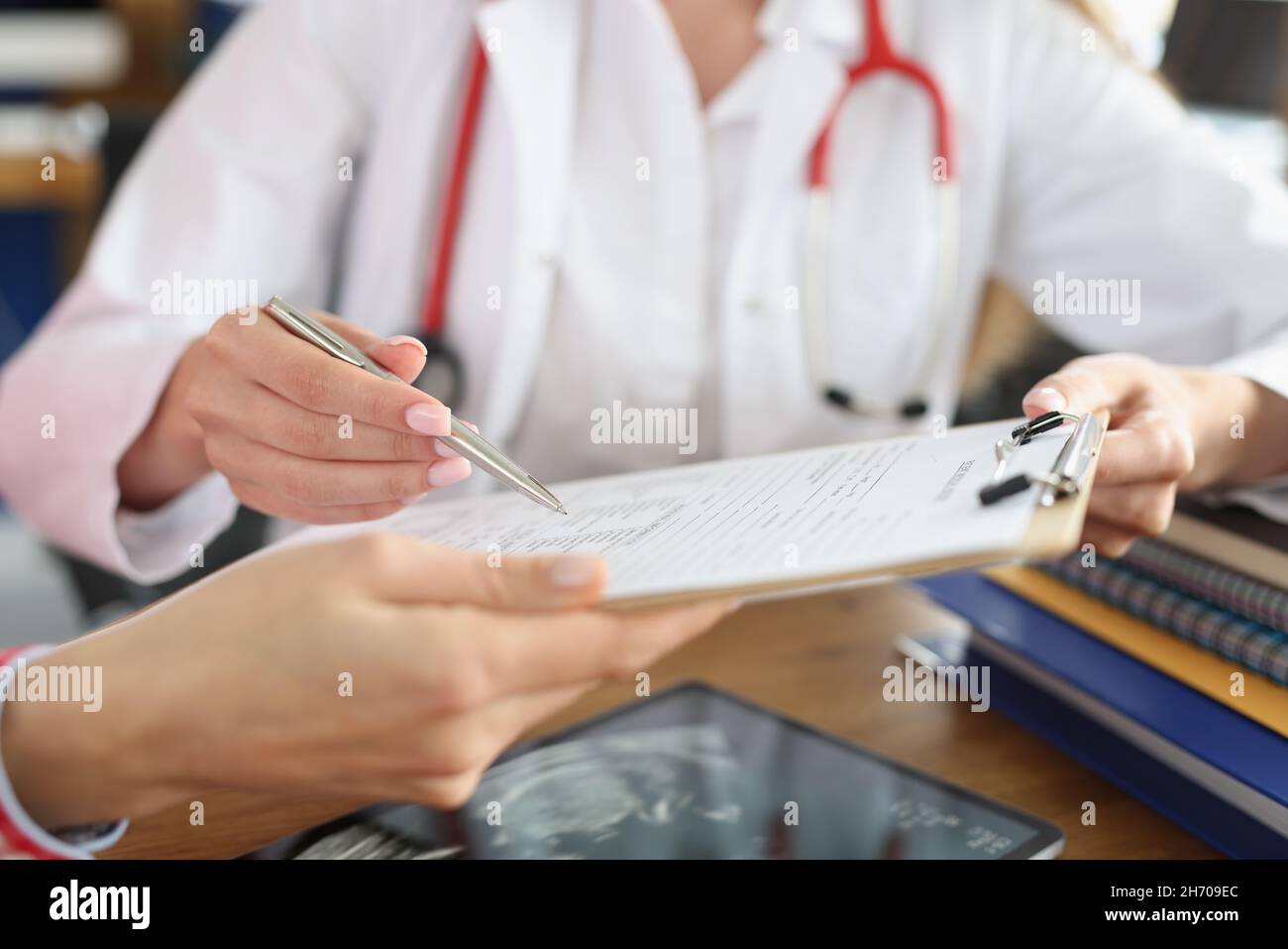 Ärztin und Patientin, die einen medizinischen Vertrag unterzeichnet Stockfoto