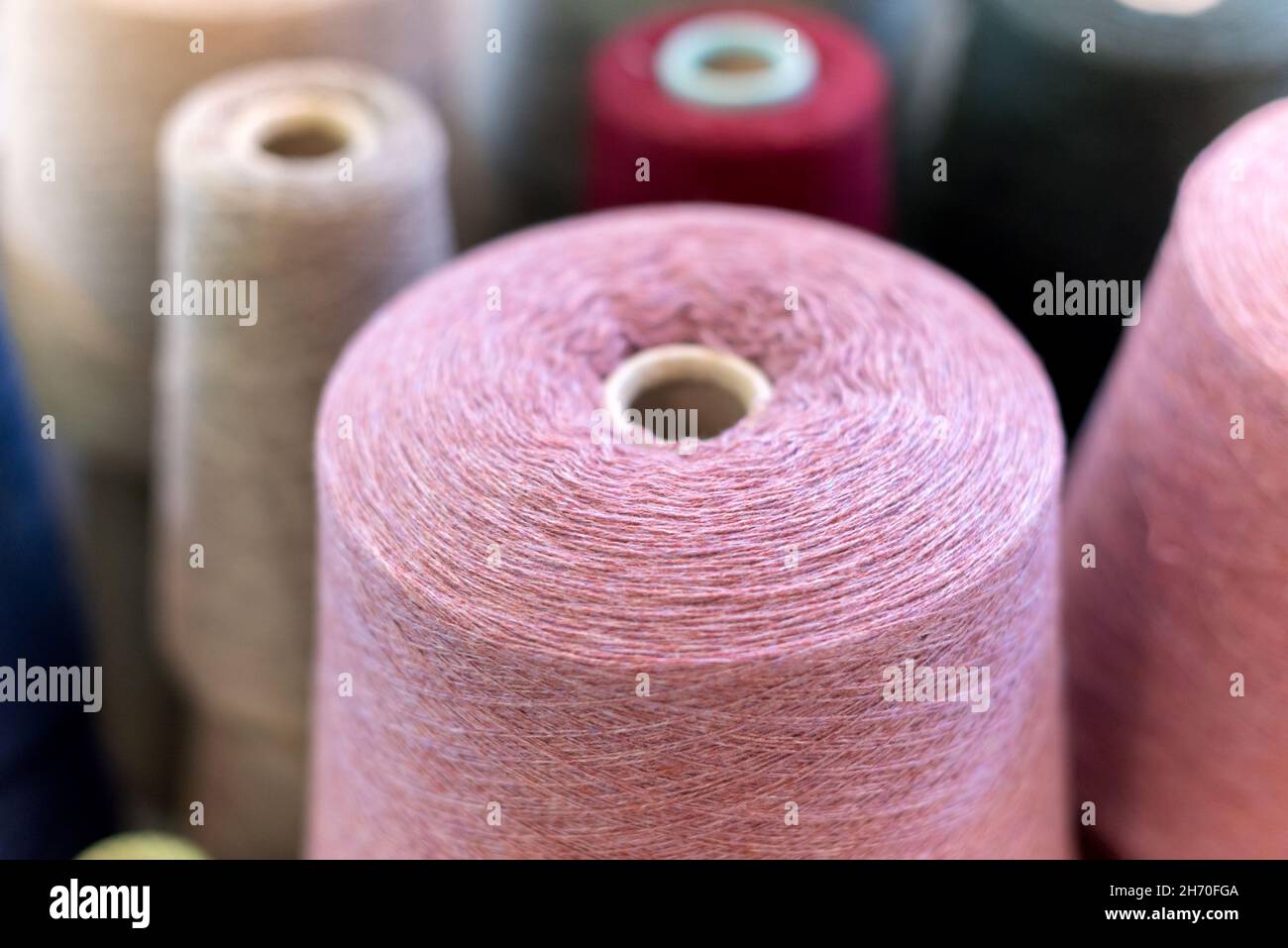 Nahaufnahme auf der Oberseite eines großen Kegels oder einer Rolle natürlicher rosa Kaschmirwolle in einer Strickfabrik mit Kopiespace Stockfoto