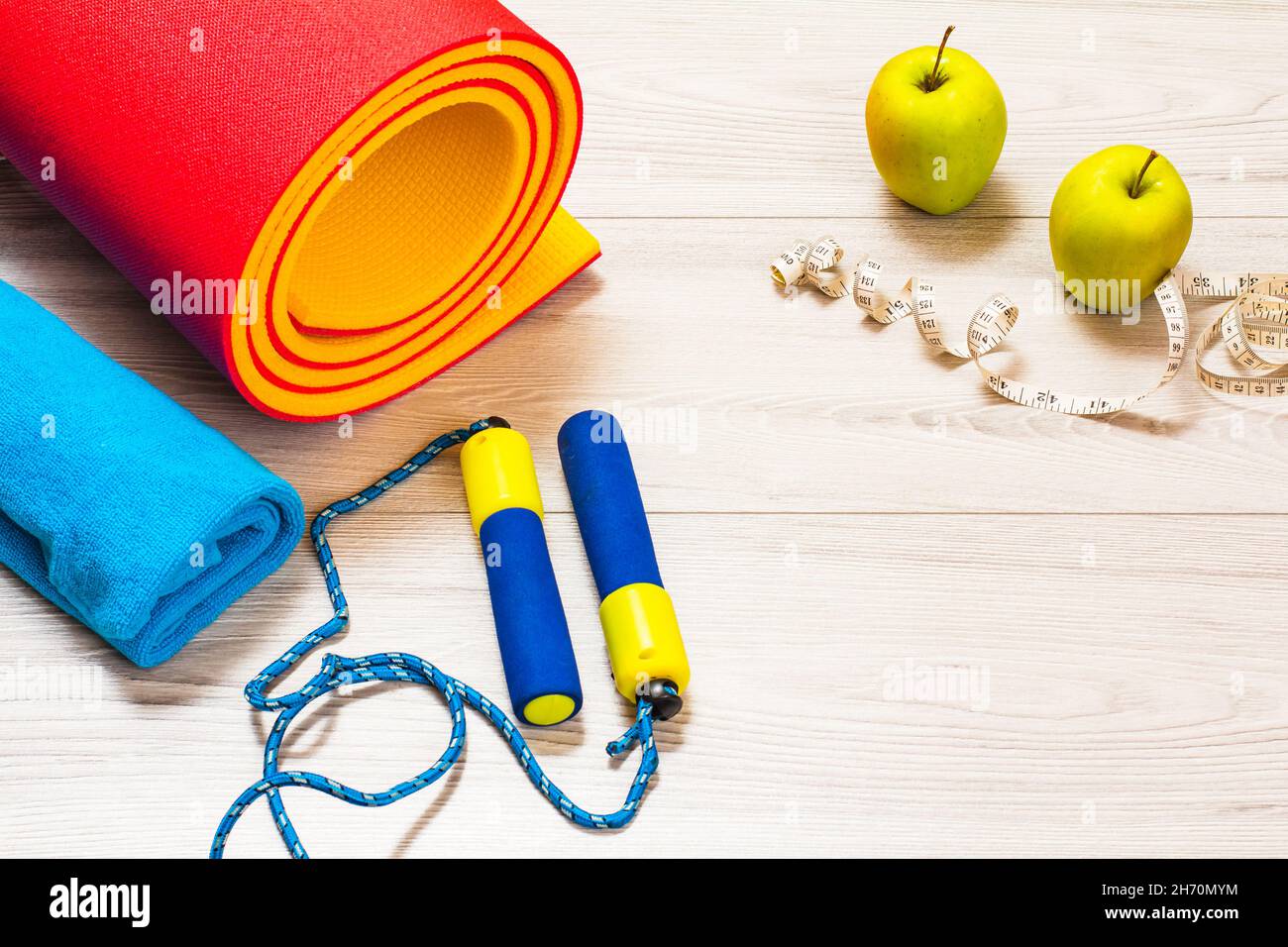 Yoga-Matte, Überspringen von Rop für Fitness, ein Handtuch, Äpfel und ein Maßband in einem Raum oder einem Fitnessraum auf dem grauen Boden. Stockfoto