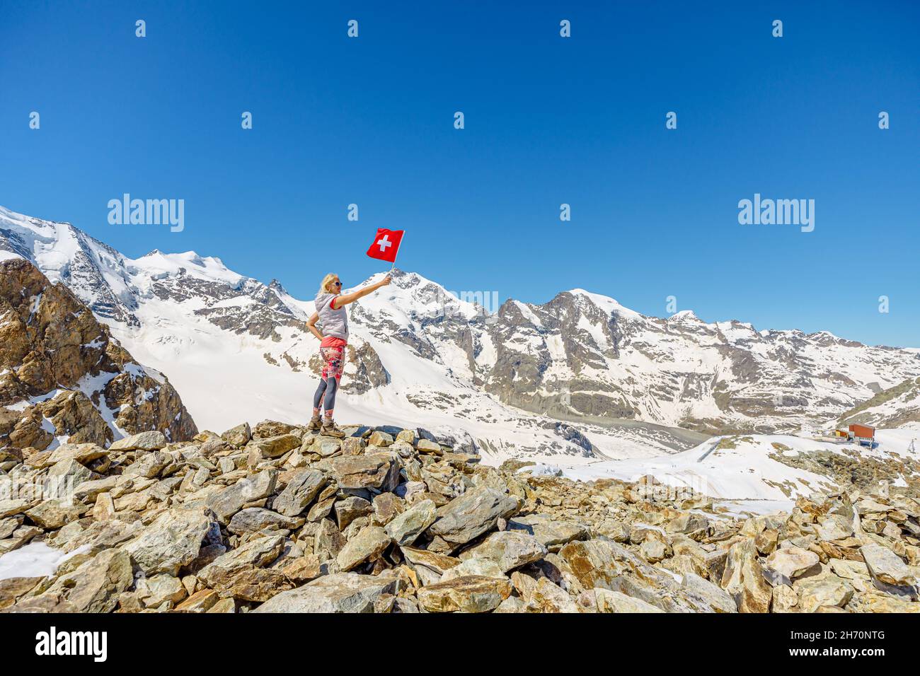 Mädchen mit Schweizer Flagge auf Sass Queder von Diavolezza in der Schweiz. Piz Bernina Skyline Blick mit Morteratschgletscher im Kanton Graubünden in Stockfoto