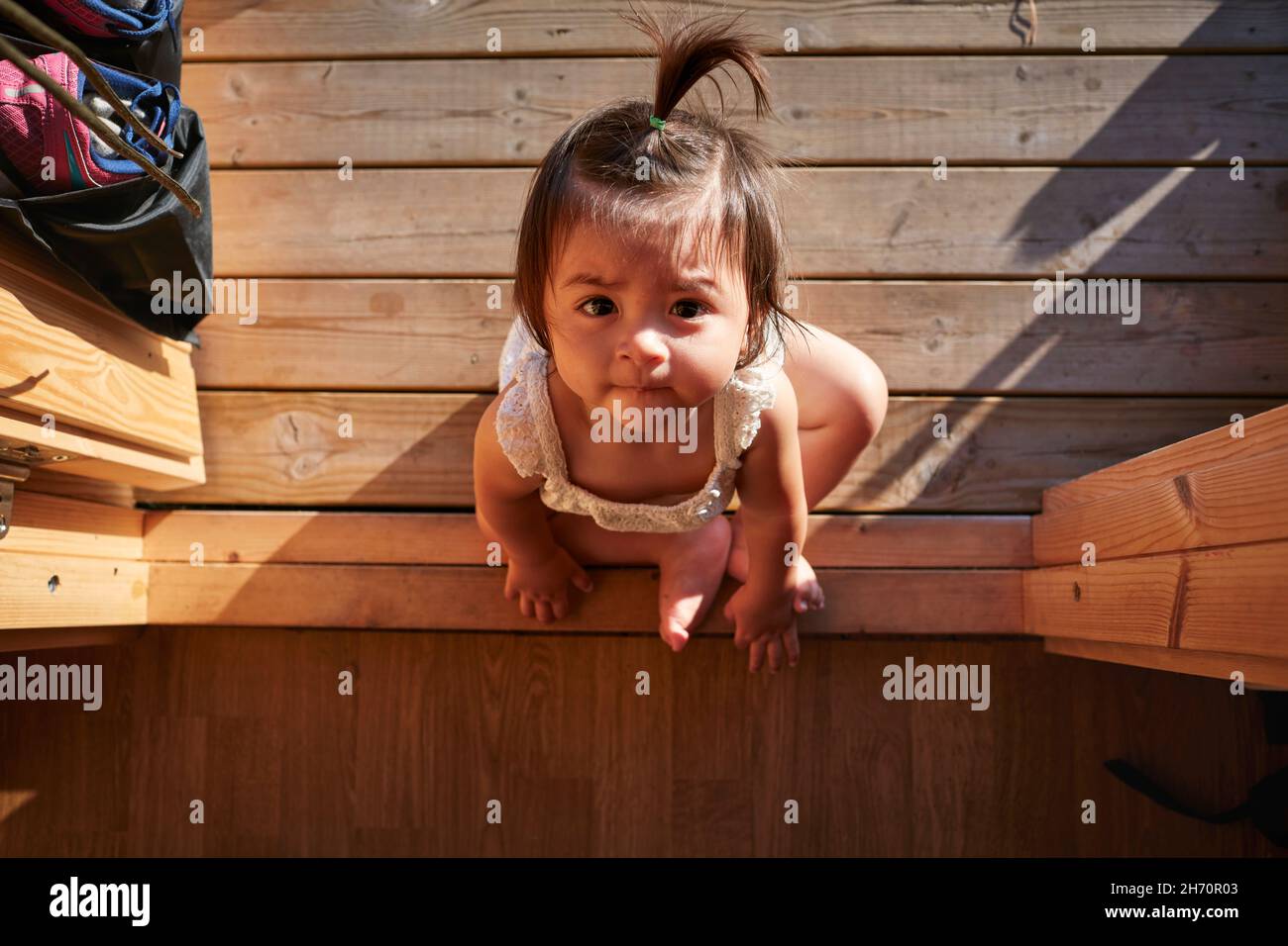 Baby Mädchen auf Holzdeck sitzen Stockfoto