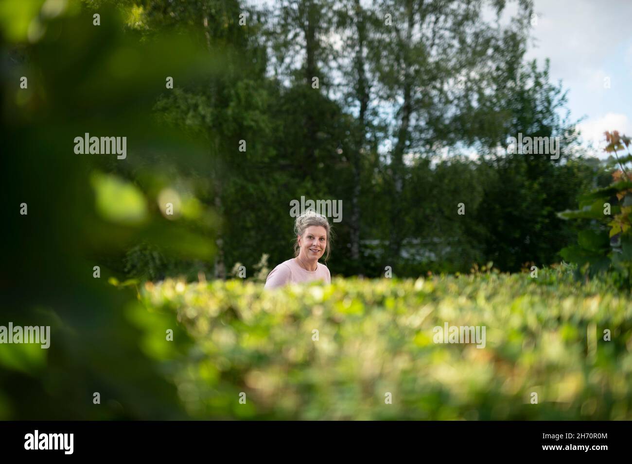 Frau im Garten mit Blick auf die Kamera Stockfoto