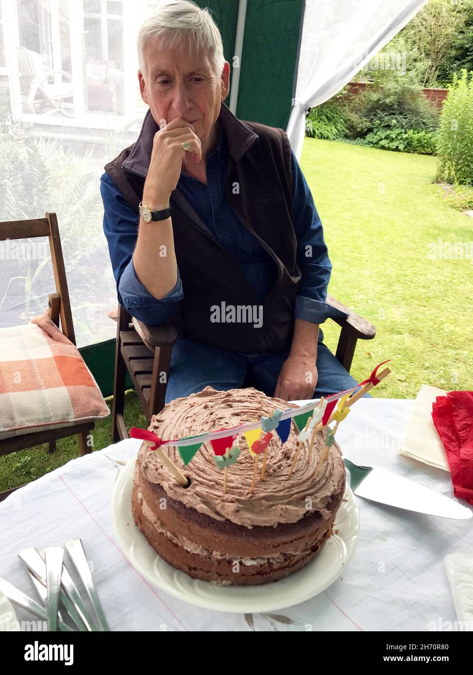 Mann mit Schokolade Geburtstagskuchen im Garten Gaceebo Stockfoto
