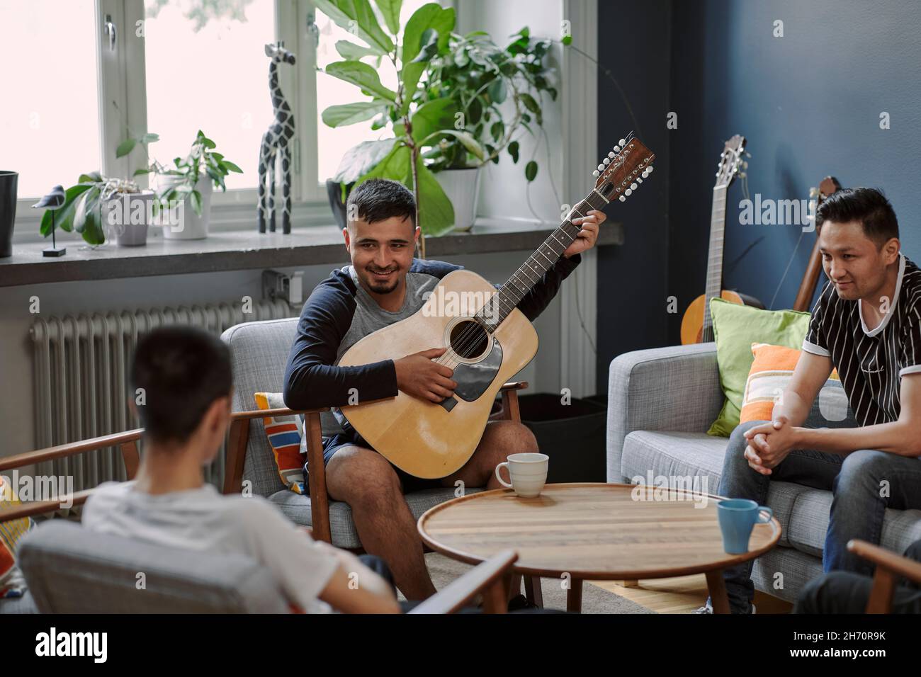 Junge Männer sprechen im Wohnzimmer Stockfoto
