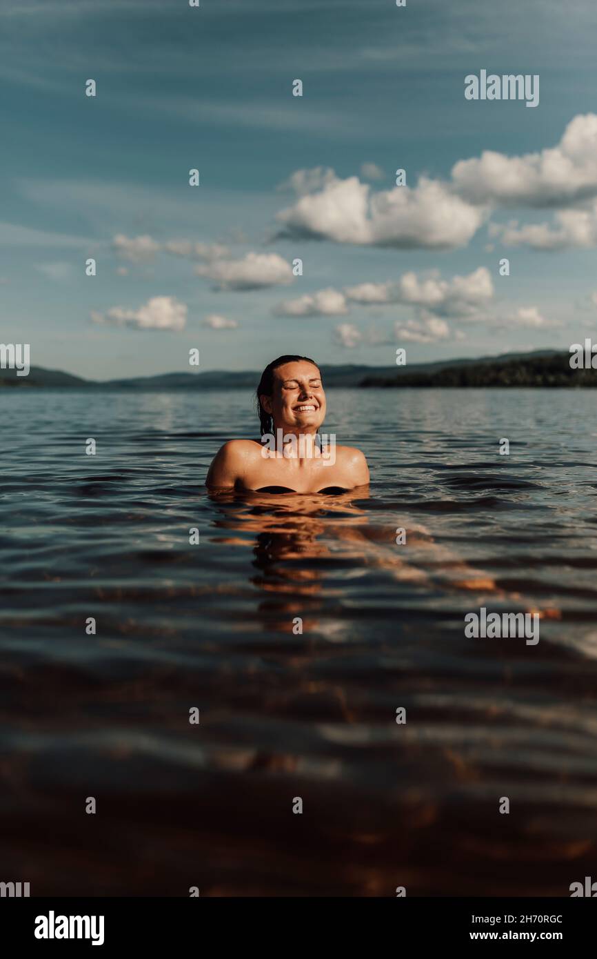 Lächelnde Frau, die sich im See entspannt Stockfoto