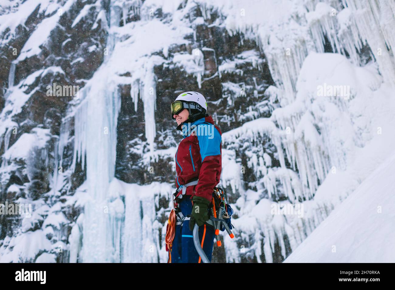 Eiskletterin, die an einer eisigen Klippe steht Stockfoto