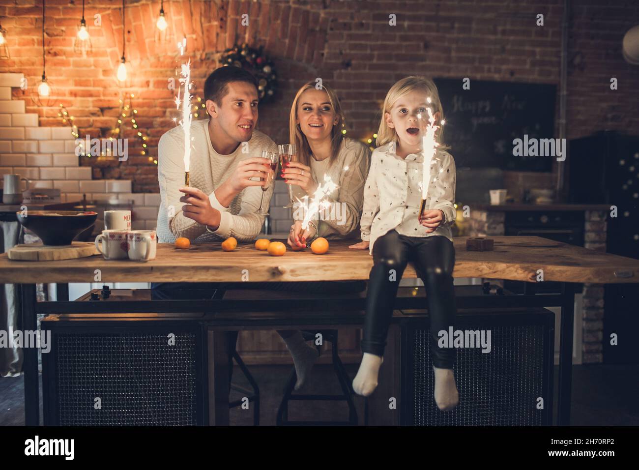 Glückliche Familie - Mutter, Vater und Tochter halten Wunderkerzen auf dem Hintergrund eines in der Küche Stockfoto