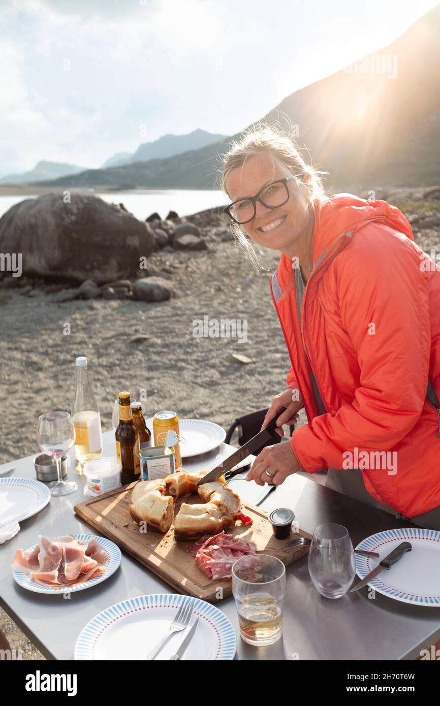 Lächelnde Frau, die am See Essen zubereitete Stockfoto