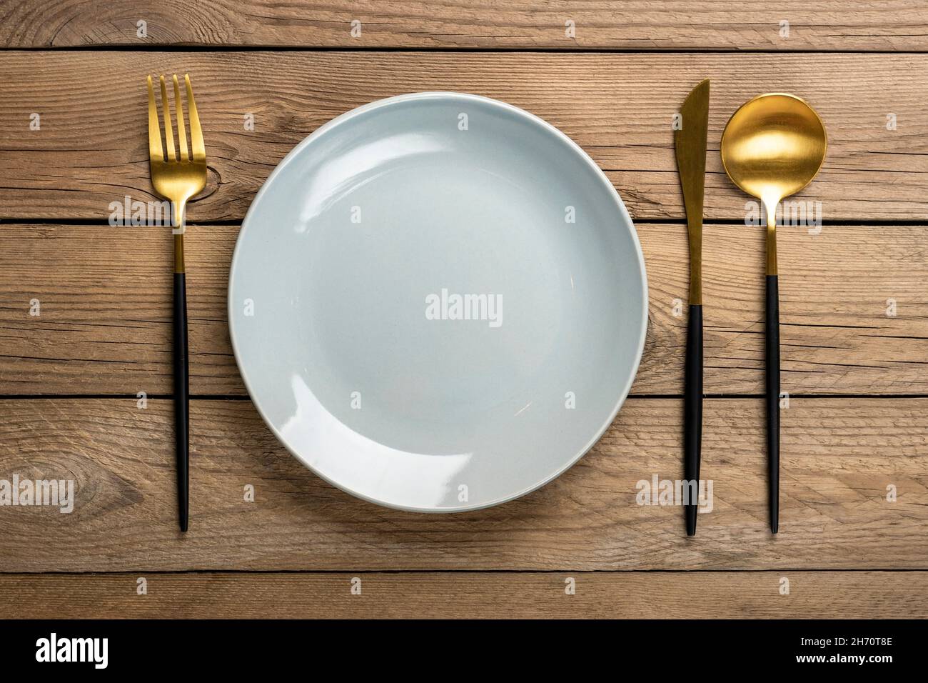 Leere runde graue Platte, Gabel, Messer, Löffel auf Holztisch Draufsicht flache Teller zum Frühstück, Mittag- oder Abendessen Mock up. Stockfoto