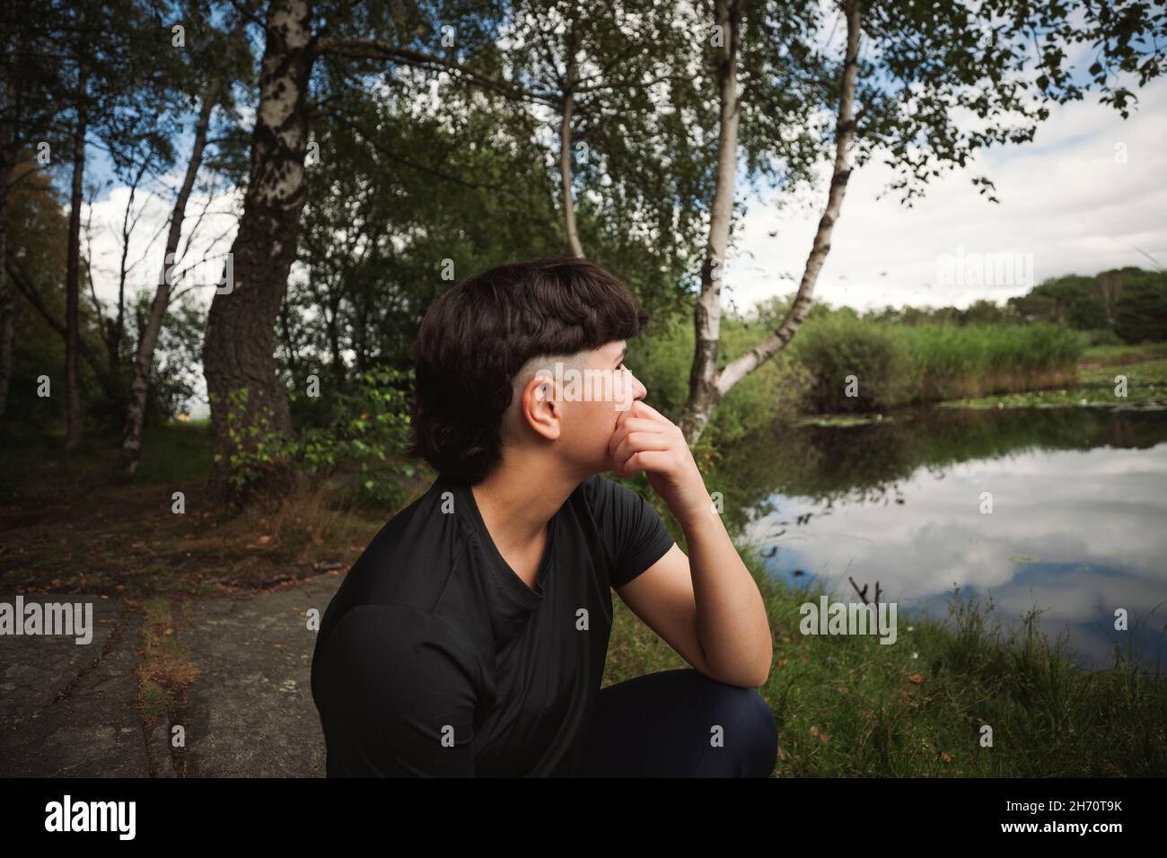 Junge Frau, die sich am Seeufer entspannt Stockfoto