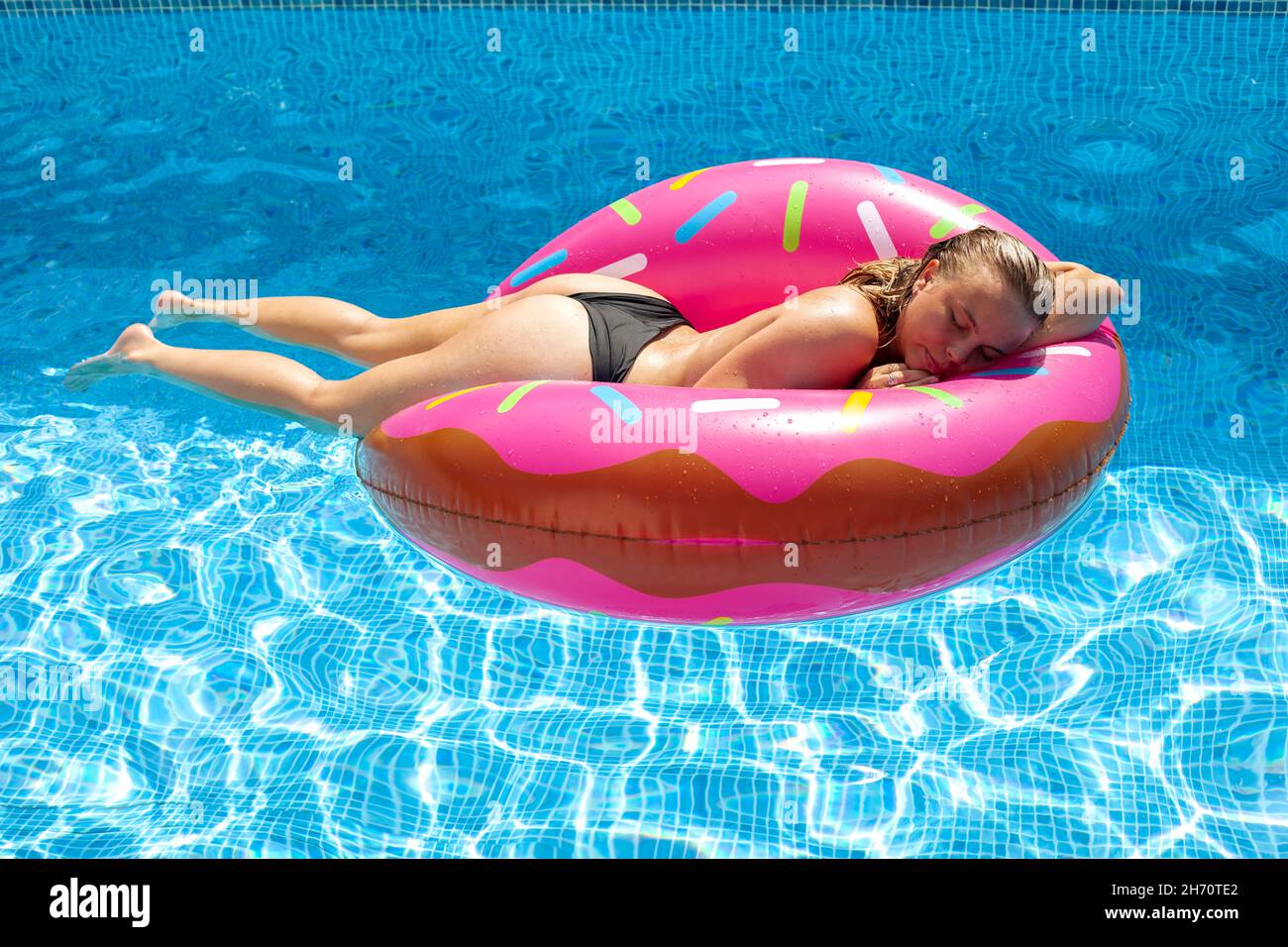 Frau, die im Pool auf der Wasserfloatie schläft Stockfoto
