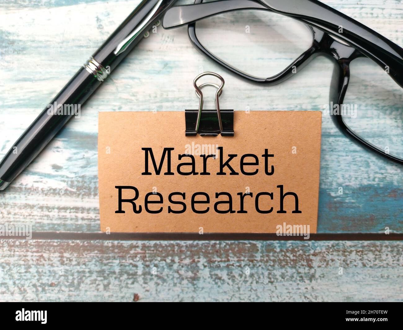 Stift, Brille und braune Karte mit Text Market Research auf Holzhintergrund geschrieben. Geschäftskonzept. Stockfoto