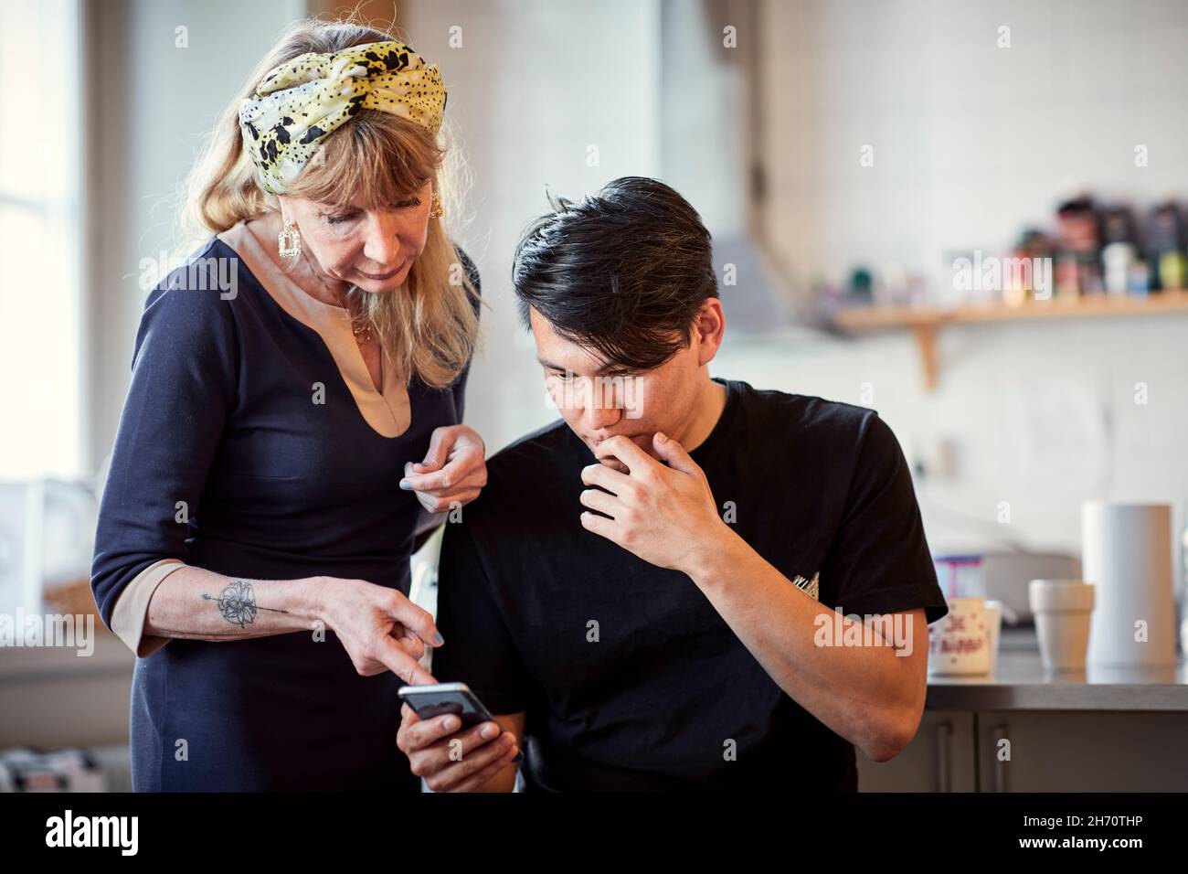 Frau zeigt Mann Dinge auf dem Handy Stockfoto