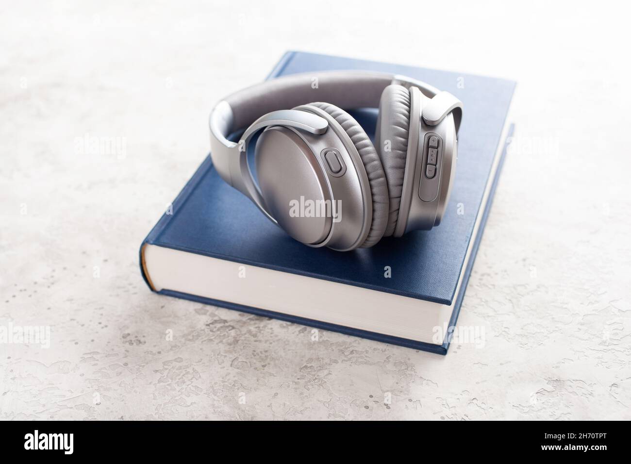 Hörbuchkonzept moderne drahtlose Kopfhörer und Buch Stockfoto