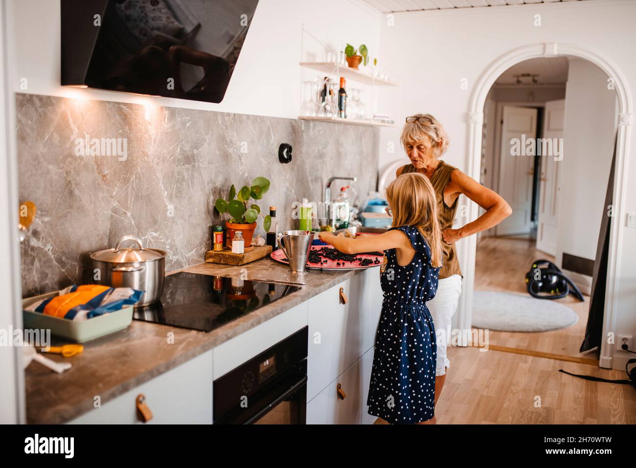 Großmutter mit Enkelin, die Essen in der Küche zubereitet Stockfoto