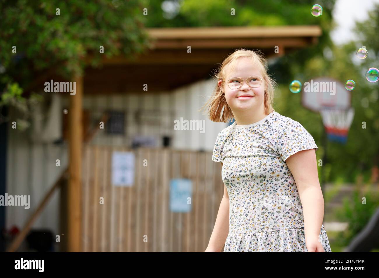 Lächelndes Mädchen, das Seifenblasen ansieht Stockfoto