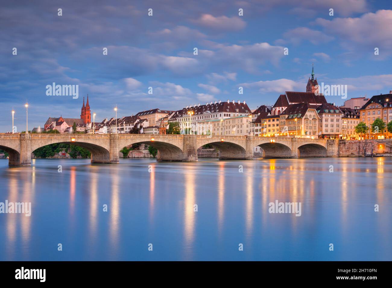 Blick auf die beleuchtete Altstadt von Basel mit dem Basler Münster, der Martins-Kirche, der Mittleren Brücke und dem Rhein bei Nacht. Schweiz.. Stockfoto